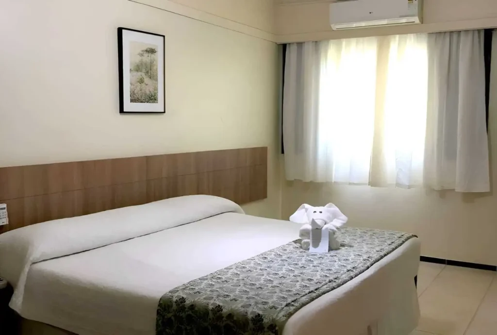 Apartamento Duplo Superior no Hotel Colonial Iguaçu, com cama de casal, janela ampla com cortina e ambiente iluminado, ideal para duas pessoas em viagem a Foz do Iguaçu.