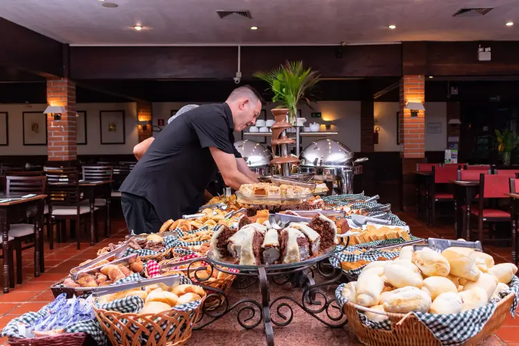 Mesa de café da manhã com pães, bolos, frutas e bebidas no Hotel Colonial Iguaçu