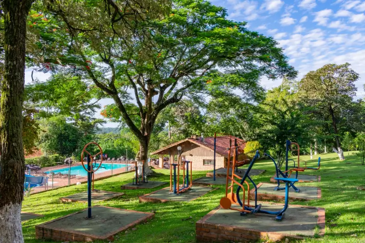 ardim arborizado com gramado e piscina ao fundo no Hotel Colonial Iguaçu