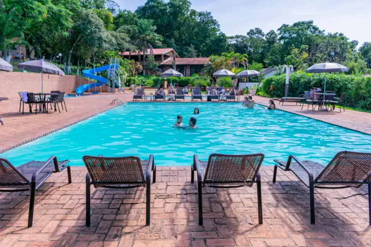 Piscina ao ar livre com ombrelones, mesas e área de convívio no Hotel Colonial Iguaçu