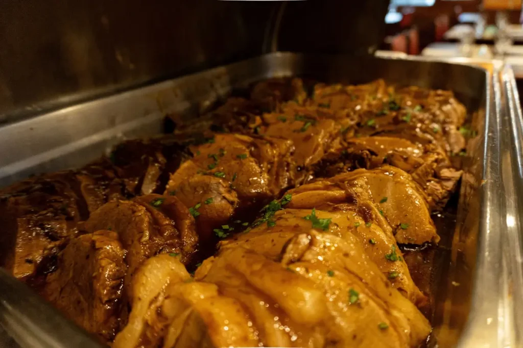 Travessa de buffet com carne assada fatiada e suculenta ao molho madeira, servida no jantar do Hotel Colonial Iguaçu.
