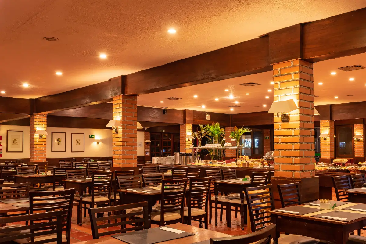 Salão amplo do restaurante do Hotel Colonial Iguaçu com decoração rústica, vigas de madeira e ambiente familiar.