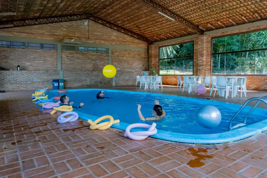 Piscina interna do Hotel Colonial Iguaçu com mesas e espaço de convivência