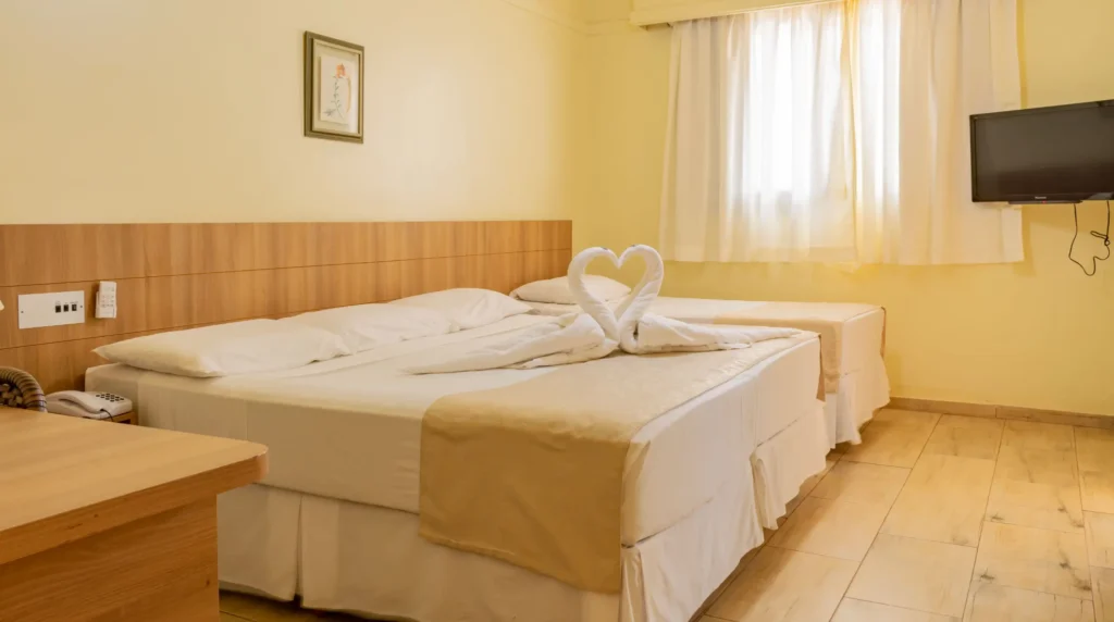 Acomodação tripla no Hotel Colonial com uma cama de casal e uma de solteiro, ideal para casais com filho, equipada com TV, telefone e mesa de trabalho.