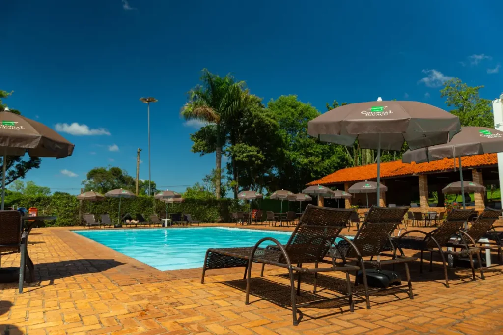 Piscina ao ar livre com espreguiçadeiras e guarda-sóis no Hotel Colonial Iguaçu