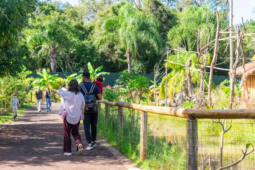 Visitantes caminhando por trilha arborizada no Eco Park Foz